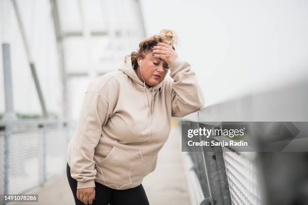 bese mujer hispana descansando después de hacer ejercicio al aire libre - obesidad fotografías e imágenes de stock