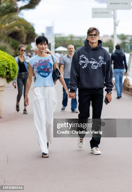 Couple Grace Elizabeth wears white pants, shirt with graphic print, Chanel bag, sandals & Nicolas Krause wears black hoody on May 17, 2023 in Cannes,...