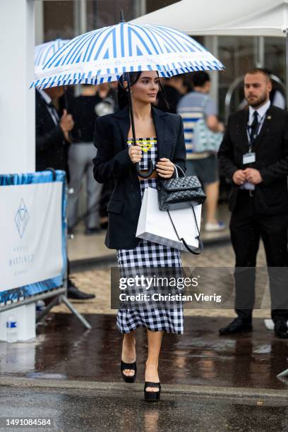 Guest wears checkered cropped top, skirt, black Chanel bag on May 17, 2023 in Cannes, France.