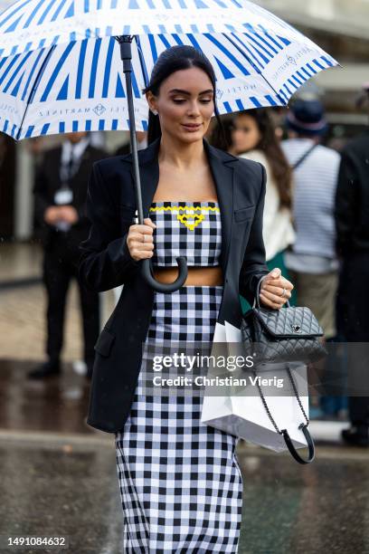 Guest wears checkered cropped top, skirt, black Chanel bag on May 17, 2023 in Cannes, France.