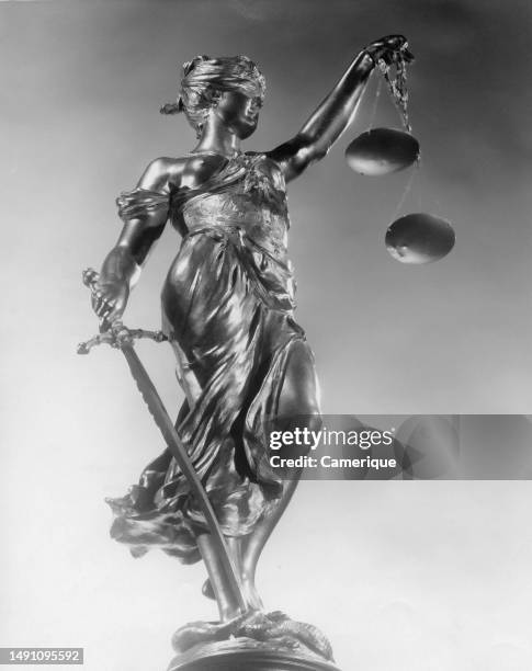 Close up of a statue of lady of justice, blindfolded holding scales and a sword