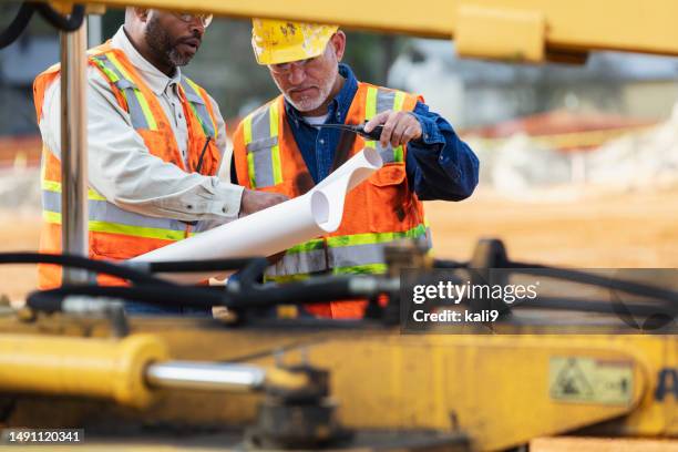 two multiracial construction workers reviewing blueprint - vägarbete bildbanksfoton och bilder