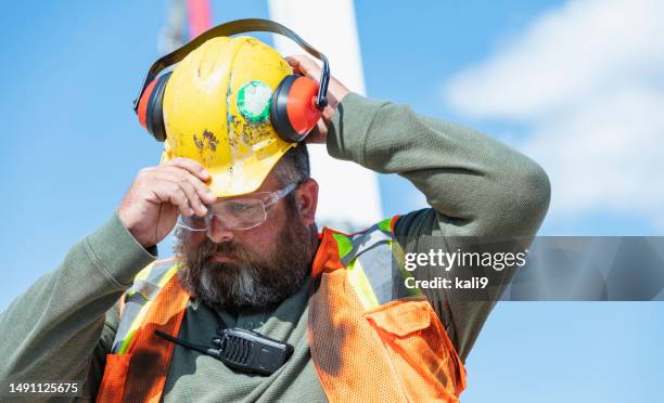 man by concrete boom pump truck, puts on hardhat - ear defenders stock pictures, royalty-free photos & images