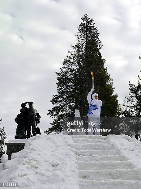 Torchbearer Dana Hunting carries the Olympic Flame at the Donner Memorial Statue during the 2002 Salt Lake Olympic Torch Relay in Truckee,...