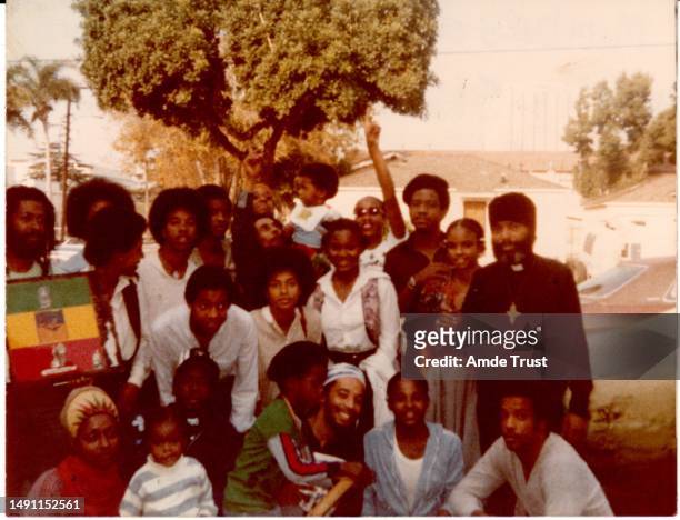 Reggae star Bob Marley in the center holding a baby on his shoulders with Fr. Amde Hamilton far right and the Saint Tekle Haymonot Ethiopian Orthodox...