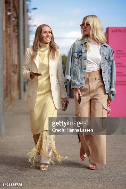 Guest wearing yellow Camilla and Marc tassel maxi dress and a guest wearing denim jacket and beige Dion Lee pants at Afterpay Australian Fashion Week...