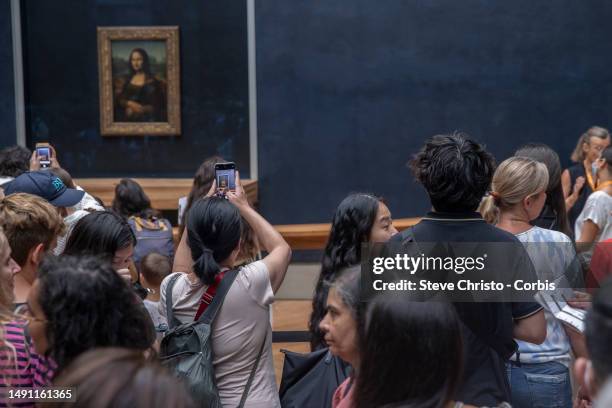 Visitors take picture of the painting "La Joconde" The Mona Lisa by Italian artist Leonardo Da Vinci on display in a gallery at The Louvre Museum in...