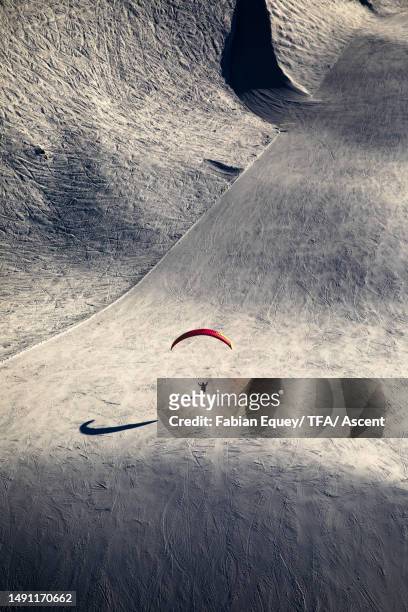 aerial view of paraglider landing on ski slope - hang parachute stock-fotos und bilder
