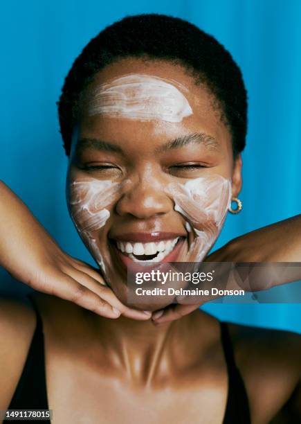 front view of a beautiful black woman laughing with her eyes closed as she has applied facial mask as she shows off her beautiful smile stock photo - peeling off bildbanksfoton och bilder