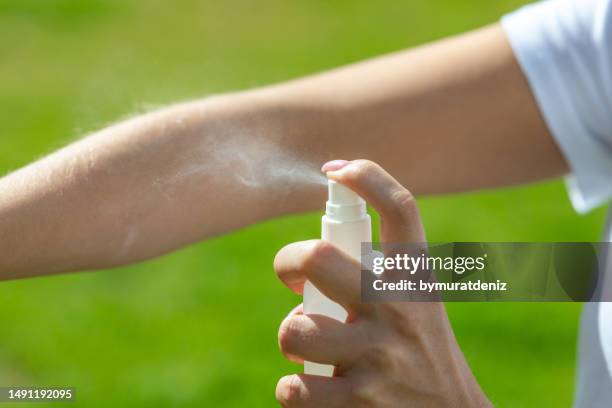 woman spraying mosquito insect repellen - fly spray stock pictures, royalty-free photos & images