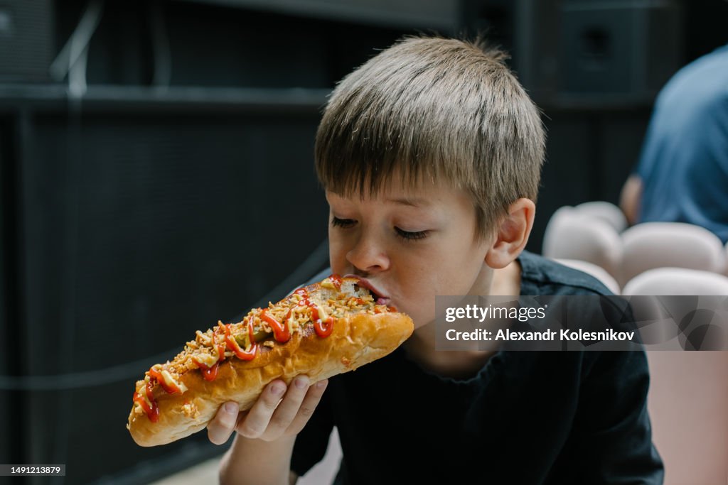 Caucasian boy 8-9 years eating a hot dog
