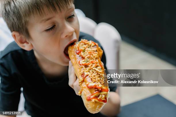 caucasian boy 8-9 years eating a hot dog - asian eating hotdog stockfoto's en -beelden