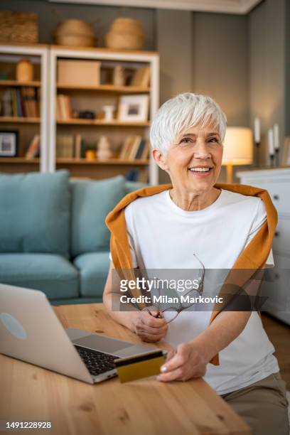 ritratto di donna anziana allegra che usa il computer portatile a casa - charming woman foto e immagini stock