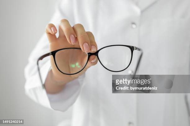 female optician hands giving new glasses to customer for testing - lens optical instrument stock pictures, royalty-free photos & images