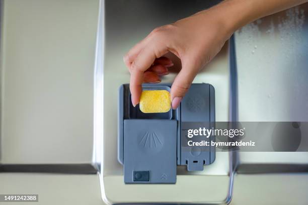füllt eine geschirrspültablette von hand in die spülmaschine - spülmittel stock-fotos und bilder
