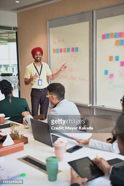 sikh man explaining importance of safety to the team of oil & gas design engineers - indian oil corporation stock pictures, royalty-free photos & images