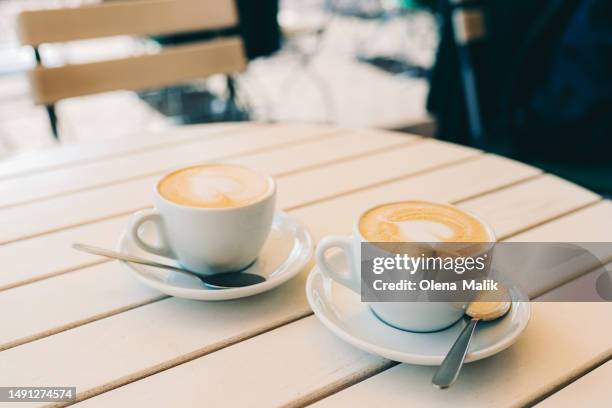 two coffee cups with latte art on the white wooden table - enjoying coffee cafe morning light stock pictures, royalty-free photos & images