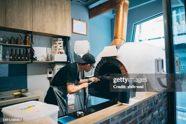 a pizza shop owner carefully inspects the preparations inside the shop before today's business hours, ensuring the integrity and availability of every equipment and ingredient. - kiln stock pictures, royalty-free photos & images