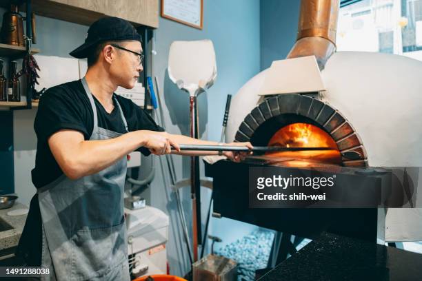 a pizza shop owner carefully inspects the preparations inside the shop before today's business hours, ensuring the integrity and availability of every equipment and ingredient. - pizzeria stock pictures, royalty-free photos & images
