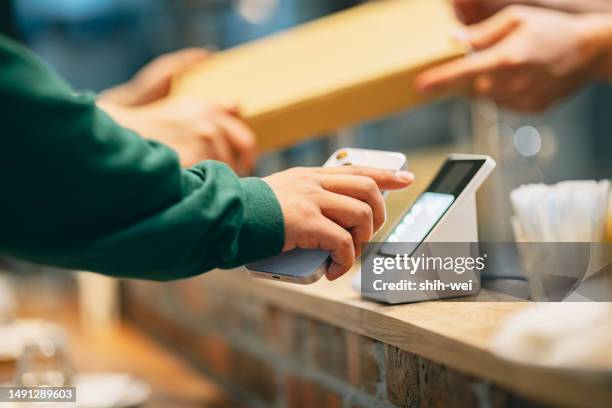 in the restaurant, a woman uses her smartphone to make a payment with the cashier. she scans the qr code using a card reader to complete a convenient contactless payment. at the same time, the cashier hands over the purchased pizza to the customer. - payment bildbanksfoton och bilder