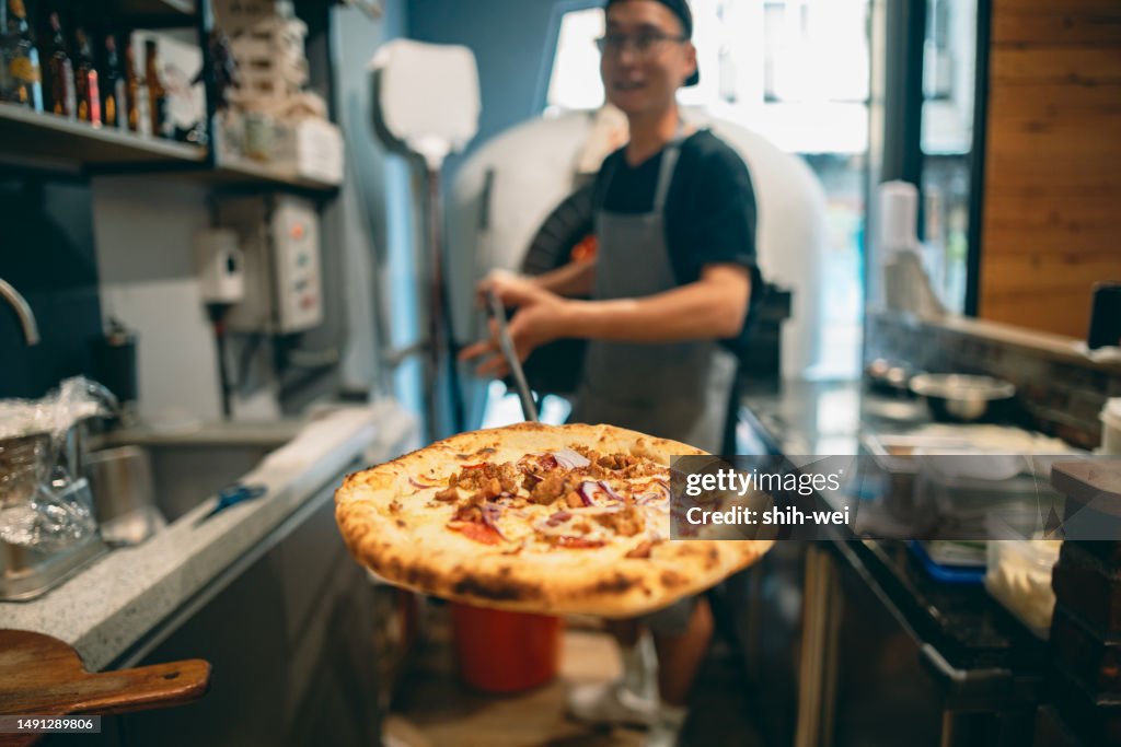 At the restaurant, a pizza chef is preparing pizza on the workstation.