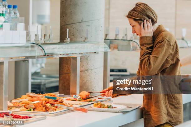 woman taking food in plate standing by buffet - platter side bildbanksfoton och bilder