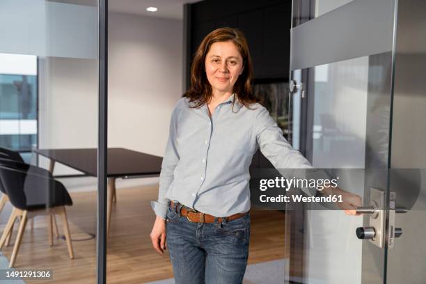 portrait of smiling businesswoman at the door in office - hemd aufreißen stock-fotos und bilder