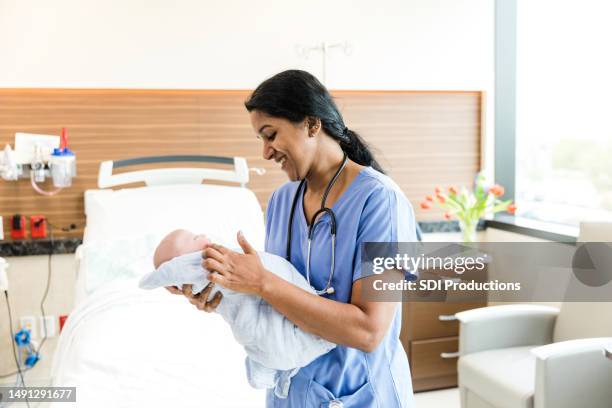 portrait mid adult midwife holding newborn - midwife stock pictures, royalty-free photos & images