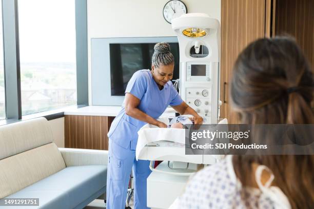 after the check-up, female doctor carefully picks up baby - midwifery stock pictures, royalty-free photos & images