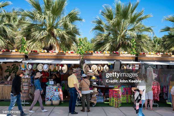 People and tourists look at hats and clothing for sale on a market stall along the Palmeral de Las Sorpresas, Promenade, Muelle Uno, harbour area on...