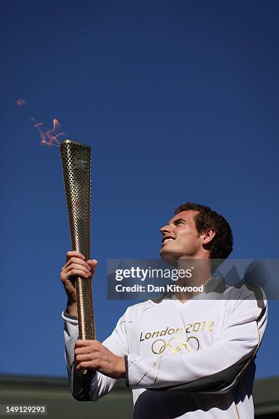 Britain's Andy Murray holds the Olympic Torch aloft on Centre Court at the All England Lawn Tennis and Croquet Club in Wimbledon on July 23, 2012 in...