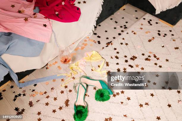 heels by wineglass and dress on carpet with confetti at home - messy house after party fotografías e imágenes de stock