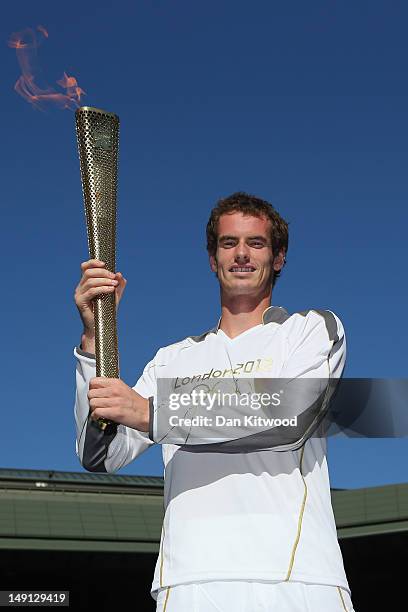 Andy Murray of Great Britain holds the Olympic Torch aloft on Centre Court at the All England Lawn Tennis and Croquet Club in Wimbledon on July 23,...