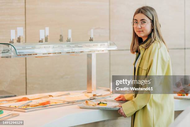 teenage girl holding tray near buffet at school cafeteria - girls lunch photos et images de collection