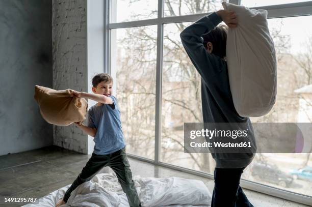 brothers doing pillow fight at home - luta de almofada imagens e fotografias de stock