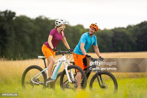 lächelndes paar radelt zusammen auf e-bikes im freien in ntaure - ebike stock-fotos und bilder