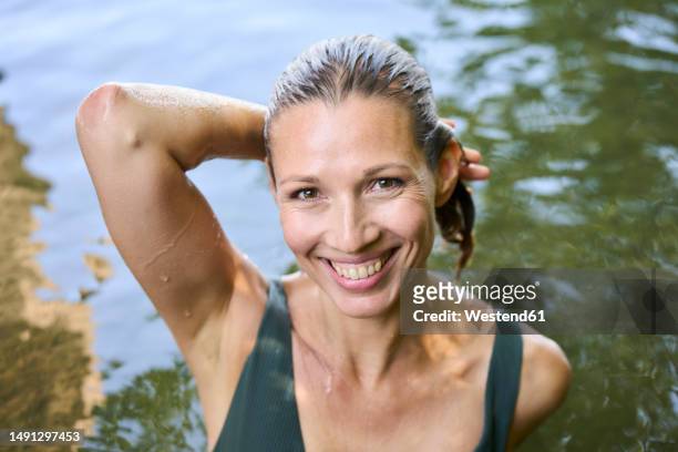 happy mature woman with hand raised in lake - older woman wet hair stock pictures, royalty-free photos & images