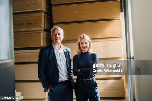businessman by smiling colleague with arms crossed in front of stacked wood - wood worker posing ストックフォトと画像