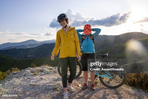 young women prepare to bike down mountain - yellow coat stock pictures, royalty-free photos & images