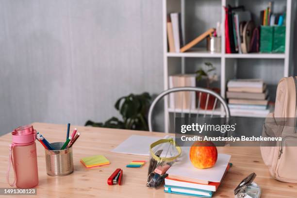wooden table with school supplies in front of a bookcase - homework table stock pictures, royalty-free photos & images