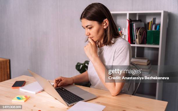 lady with hearing aid working on laptop at wooden table - hearing aid stock pictures, royalty-free photos & images