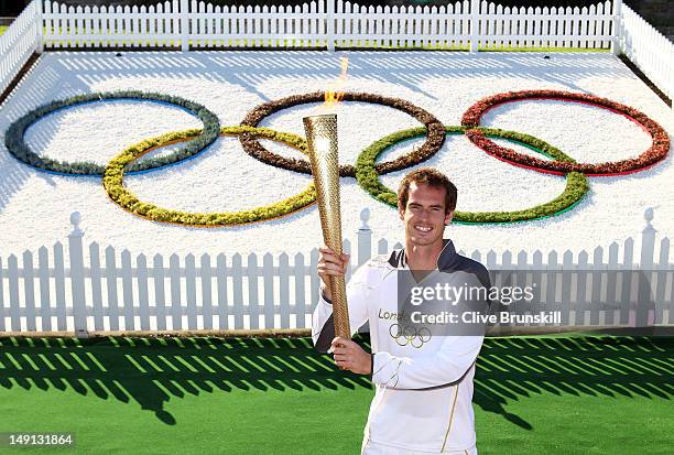 Andy Murray of Great Britain holds the Olympic Torch aloft at the All England Lawn Tennis and Croquet Club in Wimbledon on July 23, 2012 in London,...