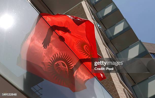 Dmitrii Aleksandrov, a swimmer from Kyrgyzstan, hangs a flag at the Athletes' Village at the Olympic Park, Sunday, July 22 in London.