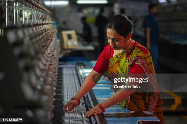 female worker operating machinery in textile factory - textile industry stock pictures, royalty-free photos & images