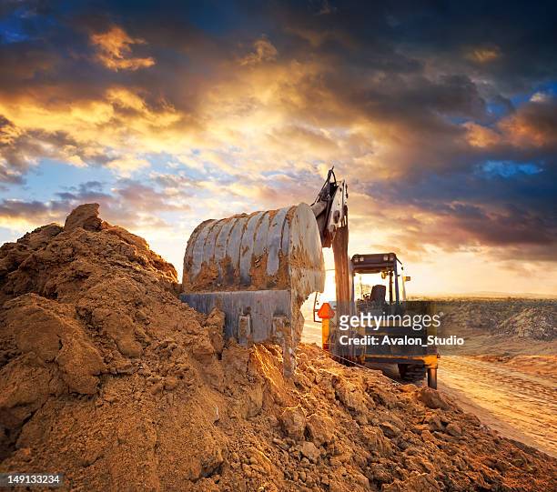 excavator on the construction site of the road against the setting sun - mining machinery bildbanksfoton och bilder