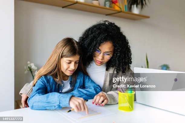 african american young woman helping her daughter doing homework school project. family, homeschool and education concept. - professor particular imagens e fotografias de stock