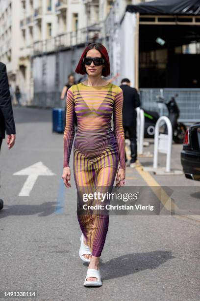 Alexandra Guerain wears transparent striped dress, white sandals during Cannes Film Festival on May 18, 2023 in Cannes, France.