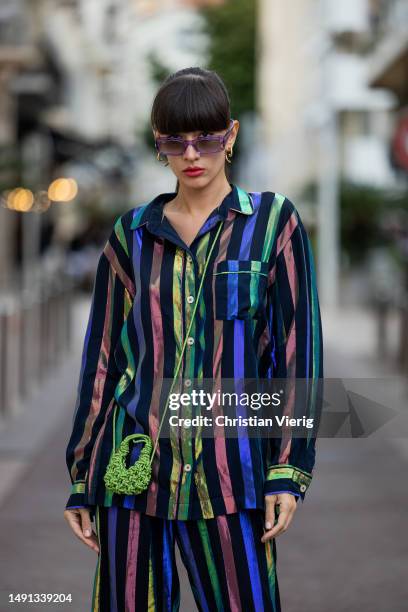Katya Tolstova wears striped button shirt & pants, green bag, platform shoes in black during Cannes Film Festival on May 18, 2023 in Cannes, France.