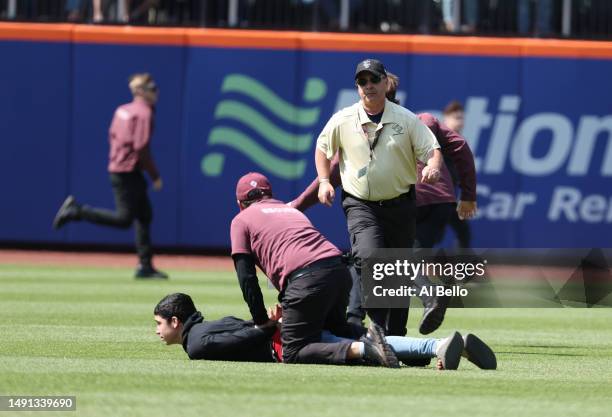 Fans run on the field during the game between the New York Mets and the Tampa Bay Rays at Citi Field on May 18, 2023 in New York City.