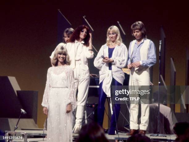British/Australian singer and actress Olivia Newton-John stands on the stage with Swedish singers and songwriters Benny Andersson, Anni-Frid...